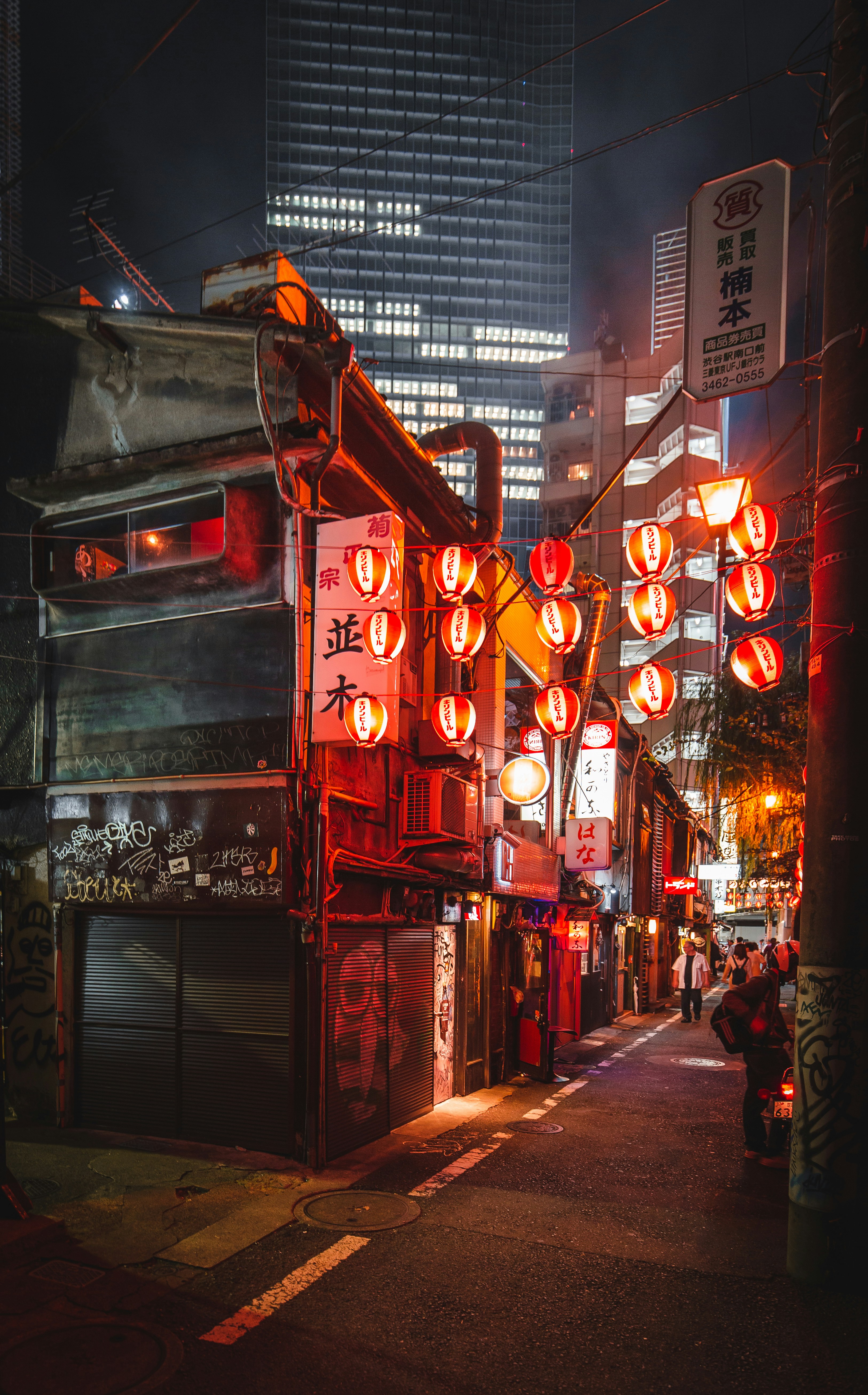 Narrow Tokyo street at night with red lanterns outside izakaya restaurants